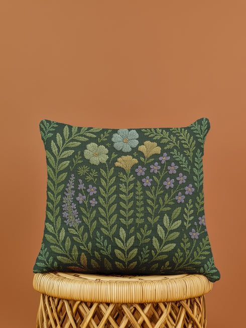 A rectangular 17x18-inch decorative throw pillow featuring a botanical woven tapestry design with embroidered flowers and leaves in green, yellow, and purple tones on a dark green background. The pillow has a double-sided print and is filled with plush poly fill, sewn closed for a soft and cozy finish. Ideal for whimsigoth decor, garden-inspired living spaces, or as a thoughtful embroidered home gift.